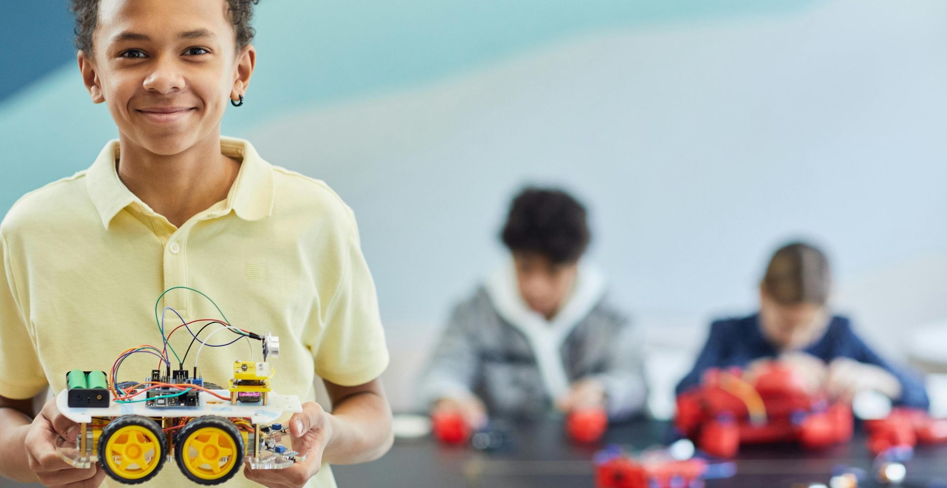 Smiling student holds robotics project during a hands-on STEM activity in the classroom.