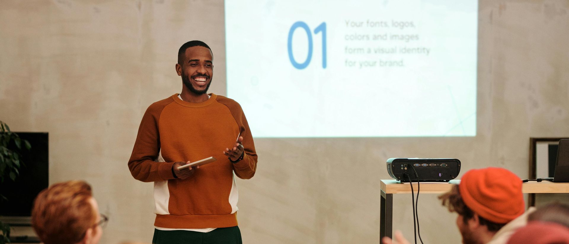 A man delivers a presentation in a modern office to a diverse group of colleagues.