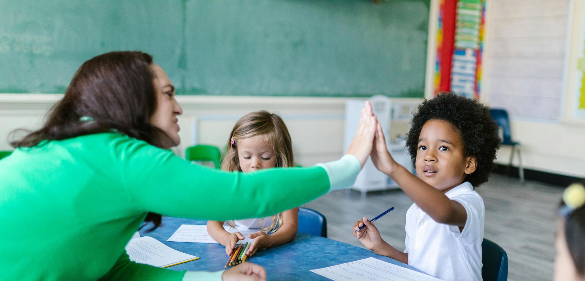A teacher and students enjoying a high five during a classroom learning activity.